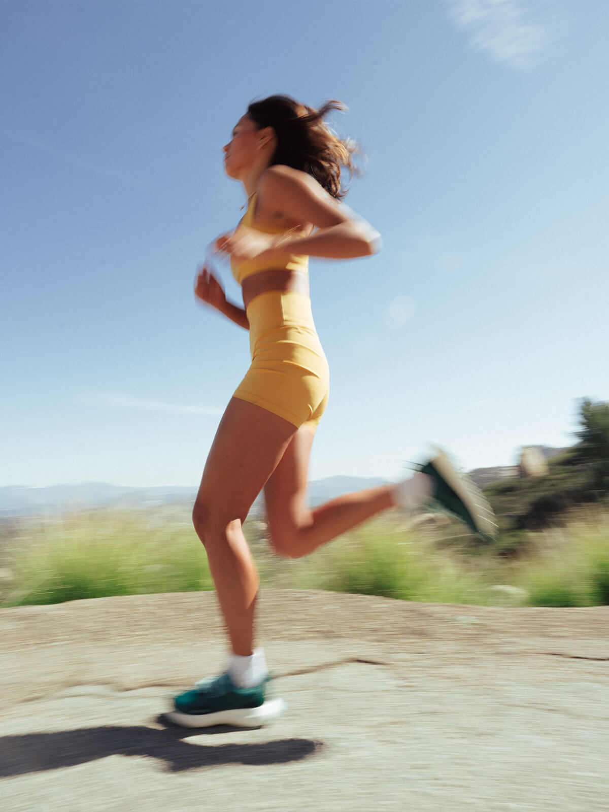 Blurred image of woman running in green Hilma running shoes