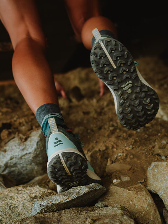 The Wildbound trail running shoe on a woman running on rocks