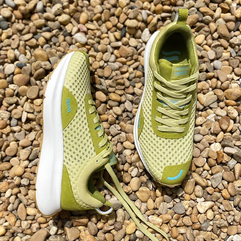 A pair of Linden Green Hilma running shoes on rocks